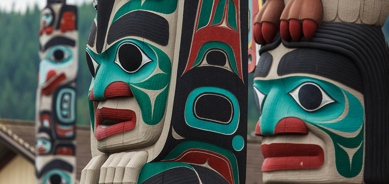Close up view of totem pole with teal, blank, and red paint.